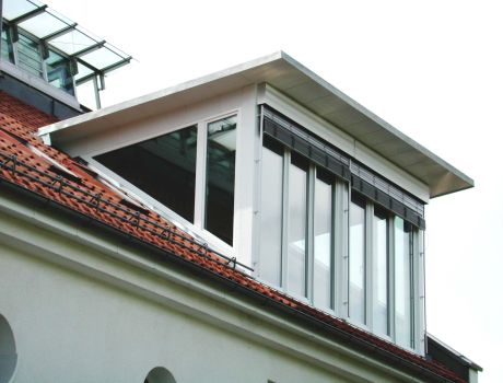 Seitlich verglaste Dachgaube mit Flachdach und weißem Fensterrahmen im Münchener Wohnhaus